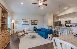 a living room with a blue couch and a kitchen with a table and chairs