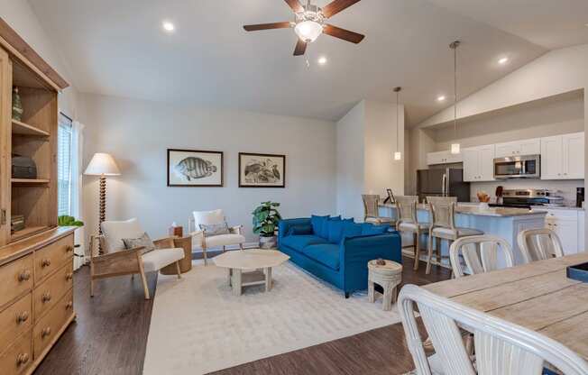 a living room with a blue couch and a kitchen with a table and chairs