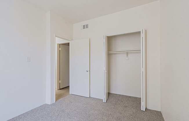 a bedroom with white walls and a closet with two doors