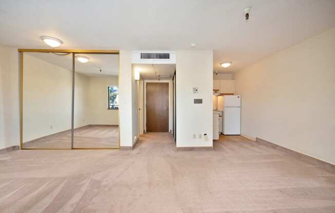 an empty living room with a large mirror and a kitchen