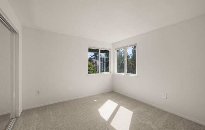 A room with a carpeted floor and two windows letting in natural light at Clackamas Trails Apartments, Oregon, 97222