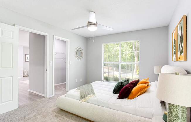 A bedroom with a bed, pillows, and a ceiling fan.