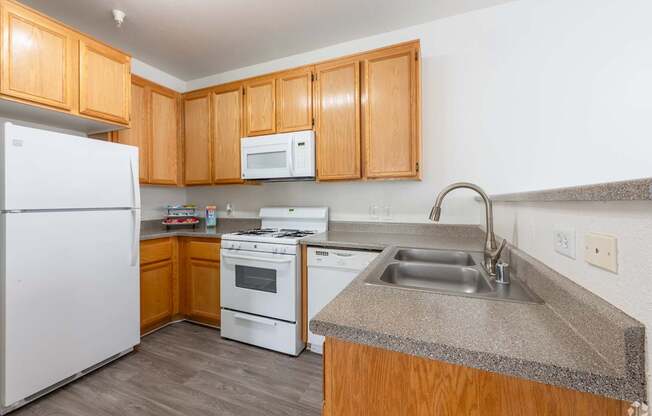 A kitchen with white appliances and wooden cabinets.