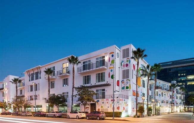 a city at night with cars parked in front of a building