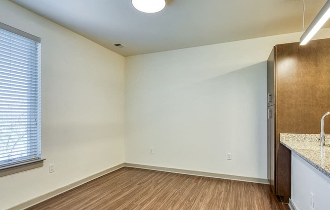 an empty living room with a kitchen and a large window