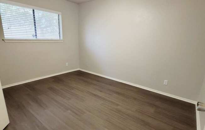an empty living room with wooden floors and a ceiling fan