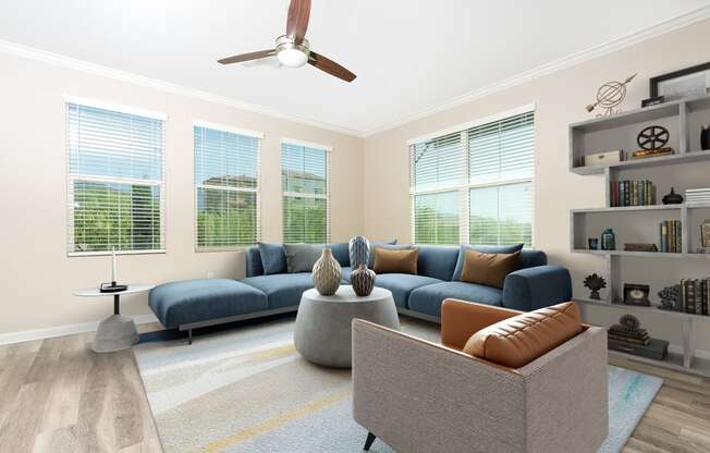 a living room with four windows and a ceiling fan