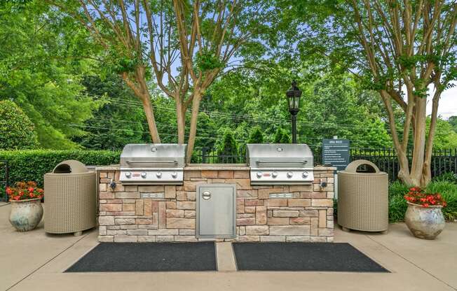 a bbq area with a stone wall and two grills