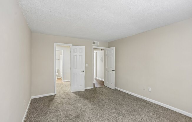 A room with carpeted floor and two open doors.