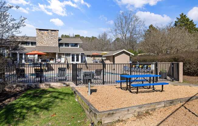 a blue picnic table in a fenced in area with a playground and a house