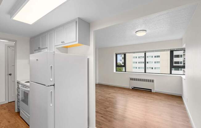 an empty living room with a refrigerator and a window