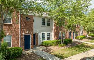 a brick building with a blue door and trees at Greens at Stonecreek, Lithonia, 30038