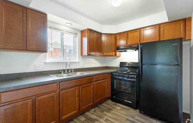 an empty kitchen with black appliances and wooden cabinets