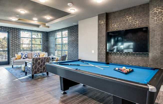 A pool table in a room with a television mounted on the wall.