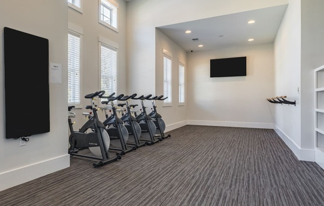 a fitness room with cardio exercise machines and a tv