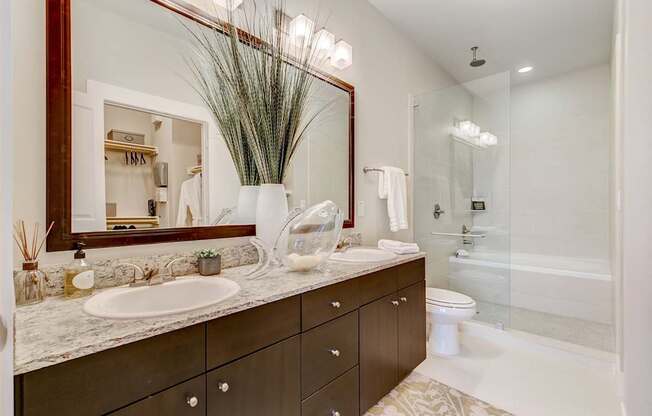 A bathroom with a sink, mirror, and a glass shower stall.