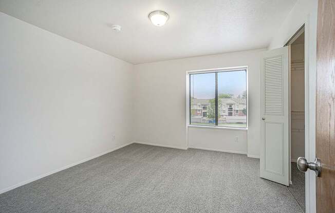 A bedroom with a carpeted floor and a window at Foxwood and The Hermitage in Portage, MI