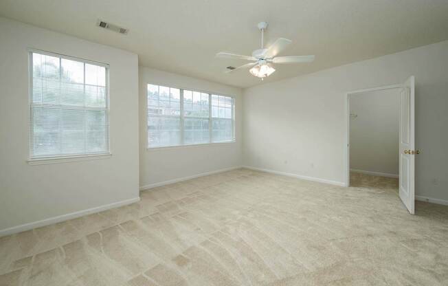 A room with a carpeted floor and a ceiling fan.