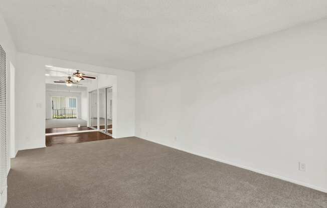 an empty living room with white walls and a ceiling fan at Olive Tree Apartments, Torrance