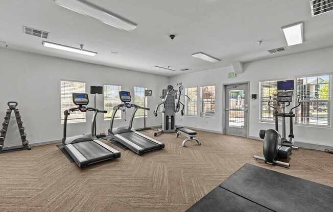 A gym with treadmills, elliptical machines, and a bench.