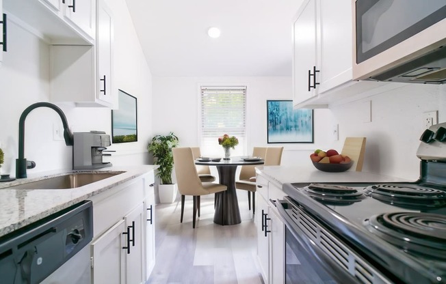 a kitchen with white cabinets and stainless steel appliances and a table with chairs