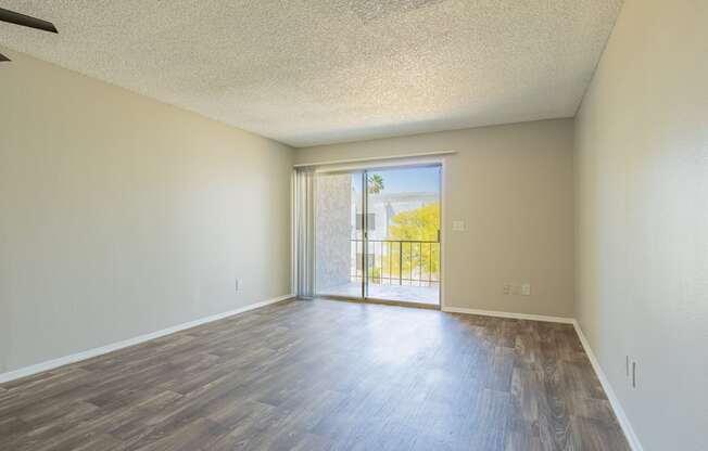 a bedroom with hardwood flooring and a sliding glass door leading to a balcony