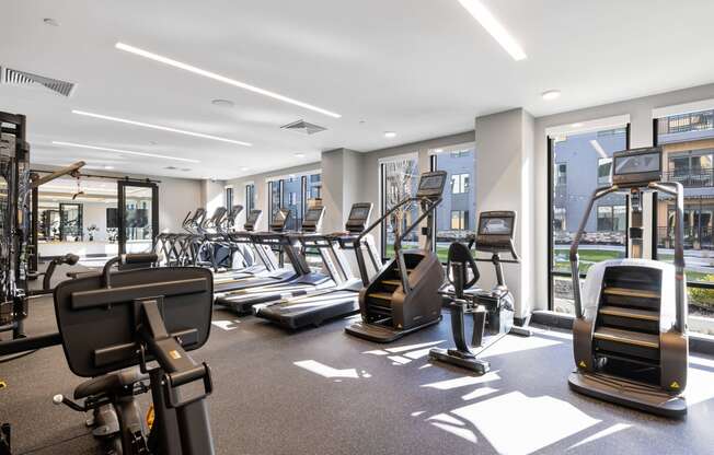 a gym with cardio equipment and windows in a building