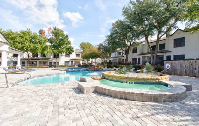 a swimming pool with a jacuzzi and a resort style pool with trees