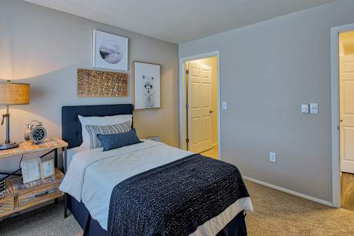 A bedroom with a bed, nightstand, and picture frames on the wall.