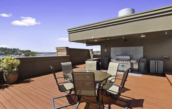 Rooftop patio area with a table and lounge chairs and a grill at Illumina Apartment Homes, WA 98102