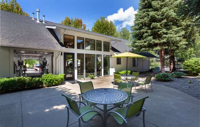 a patio with a table and chairs and a house in the background