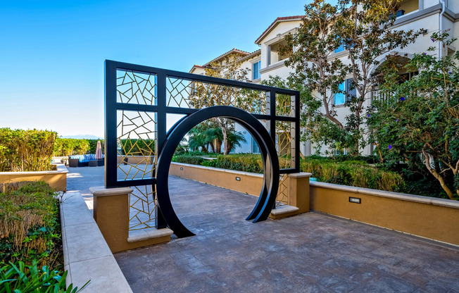 a large metal archway on a patio with buildings in the background