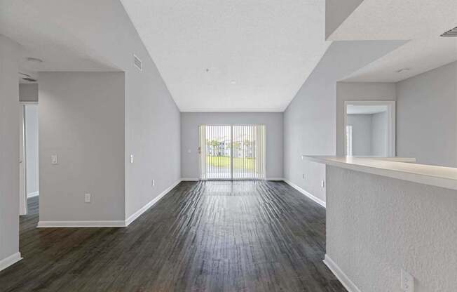 the living room and dining room of an apartment with wood flooring and a balcony