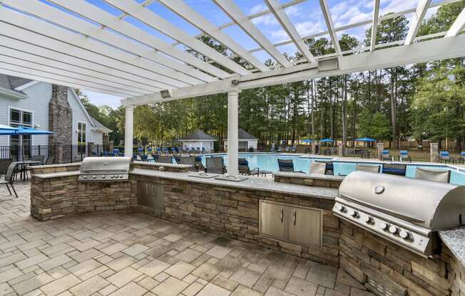 a covered outdoor kitchen with a pool in the background at Trails at Short Pump Apartments, Richmond, VA