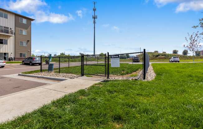 A sign is posted on a fence in front of a grassy area.