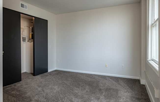 an empty living room with carpet and a door to a closet