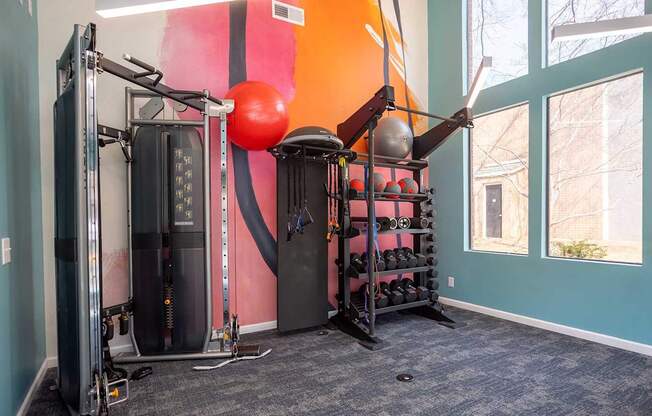 A gym room with a pink and orange wall and a variety of equipment.