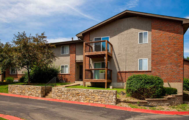A brick building with a balcony and a stone wall.