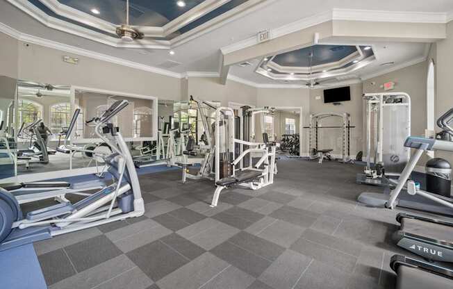 A gym with a variety of equipment including treadmills, weights, and exercise machines.