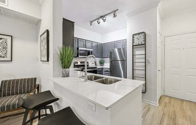 A kitchen with a white countertop and a black stool.