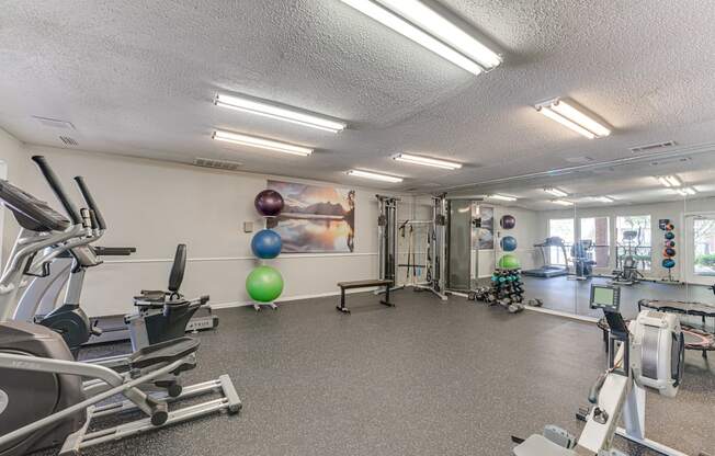 A gym with a variety of equipment including treadmills, exercise balls, and weight machines.