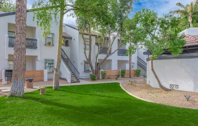 a grassy area with trees and buildings in the background