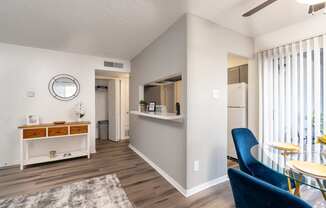 A living room with a blue chair and a glass table.