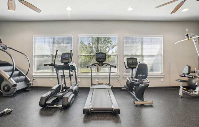 A home gym with a treadmill, elliptical trainer, and stationary bike.