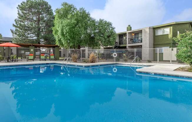 A swimming pool in front of a building with a fence around it.