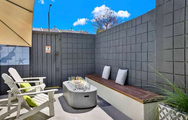 A patio with a hot tub, chairs, and a bench.