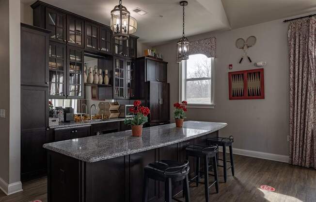 Elegant clubhouse kitchen at Queens Gate Apartments, featuring granite countertops, bar seating, and stylish cabinetry, perfect for resident events and gatherings.