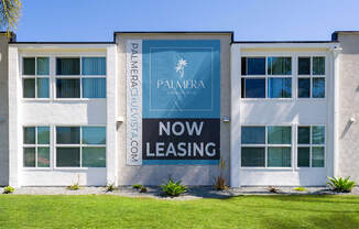 A white building with a blue sign that says Pamera now leasing.