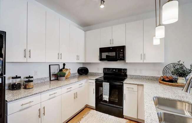 A kitchen with black appliances and white cabinets.