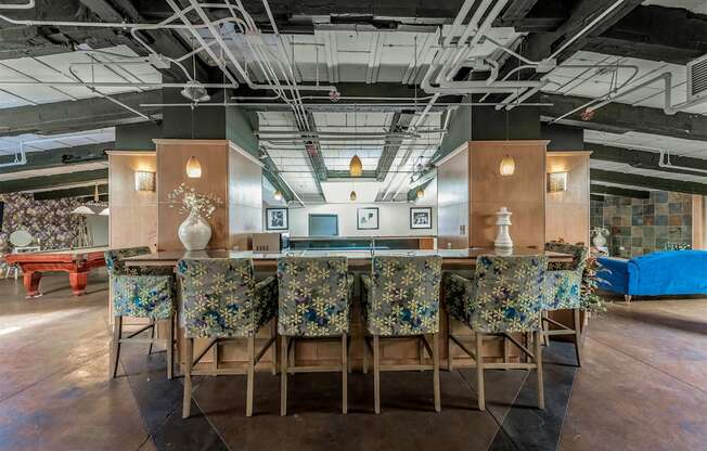 a long bar with chairs and a table in a lobby